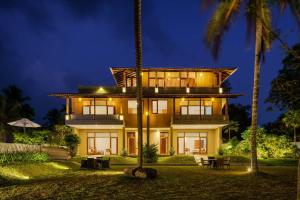a large house with palm trees in front of it at Kiss Blossom in Mirissa