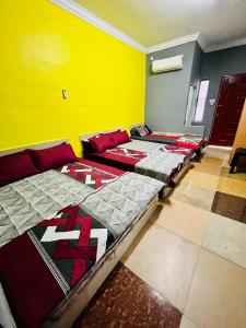two beds in a room with a yellow wall at Homestay/Bilik Teluk Gading in Kuala Rompin