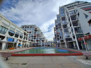 uma piscina no meio de uma cidade com edifícios em Fenestrelle By LGM 57m2 clim, wifi, ménage inclus em La Grande-Motte