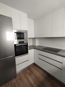 a kitchen with white cabinets and a black microwave at APARTAMENTO ANCHA CENTRO in Huétor-Tájar