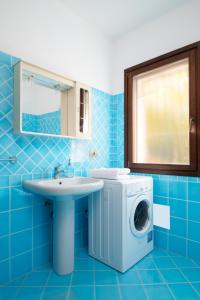 baño azul con lavadora y lavamanos en Sea Shell - Klodge en Olbia