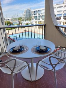 a table and chairs on a balcony with a view of the water at Fenestrelle By LGM 57m2 clim, wifi, ménage inclus in La Grande Motte