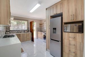 a kitchen with wooden cabinets and a white refrigerator at The Cycad. 4-Bed Home next to Clearwater Mall in Roodepoort