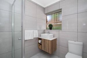 a bathroom with a toilet and a sink and a shower at The Cycad. 4-Bed Home next to Clearwater Mall in Roodepoort +18 photos