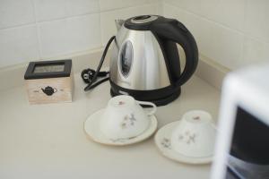 une bouilloire de thé noir et blanc et deux tasses sur un comptoir dans l'établissement Io, te e il mare, à Polignano a Mare