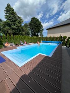 a swimming pool in a backyard with a person laying on a deck at DOMKI NA TURYSTYCZNEJ in Dąbki