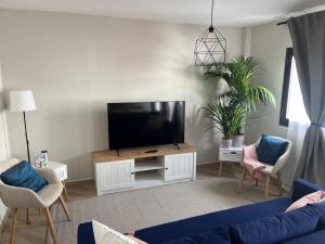 ein Wohnzimmer mit einem blauen Sofa und einem Flachbild-TV in der Unterkunft Casa Aguamarina in Corralejo