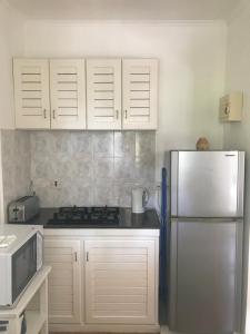 a kitchen with white cabinets and a refrigerator at Sunbird Bungalow in Anse Boileau