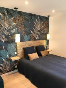 - une chambre avec un lit et un mur orné de plantes dans l'établissement Joli appartement très bien situé - Perros-Guirec, à Perros-Guirec