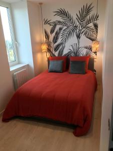 Un dormitorio con una cama roja con una planta en la pared en Joli appartement très bien situé - Perros-Guirec, en Perros-Guirec