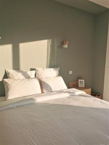 a bedroom with a bed with white sheets and pillows at Au Jardin des Deux Roches in Prissé