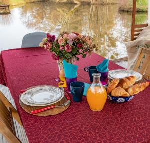 una mesa con platos y un jarrón de flores y pan en Atelier de peinture au Moulin de Gâteau - Atelier sur l'eau, en La Vallée
