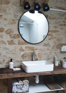 a bathroom with a sink and a mirror on a stone wall at Logement Cosy 2 à 4 Personnes Campagne proche Mer in Frossay