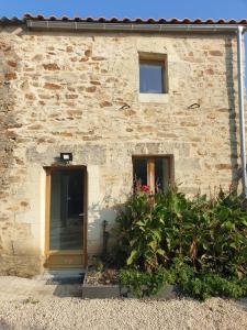 a stone building with a door and some plants at Logement Cosy 2 à 4 Personnes Campagne proche Mer in Frossay