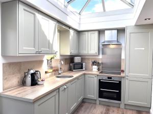 a kitchen with white cabinets and a skylight at Ardenlea in Bourton on the Water
