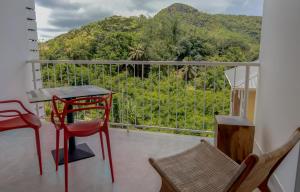 a balcony with a table and chairs and a view of a mountain at kannel Apartments in Anse Royale