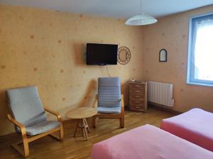 a bedroom with two chairs and a tv on the wall at Résidence L'Alexandra 2 étoiles in Bourbonne-les-Bains