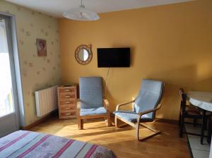 a bedroom with two chairs and a tv on the wall at Résidence L'Alexandra 2 étoiles in Bourbonne-les-Bains