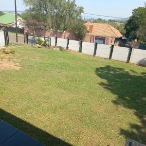 a grassy yard with a fence and a tree at Alo guesthouse in Pietermaritzburg