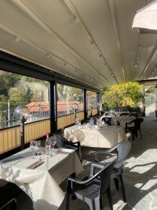 un restaurant avec des tables blanches, des chaises et des fenêtres dans l'établissement Delzanno, à Varallo