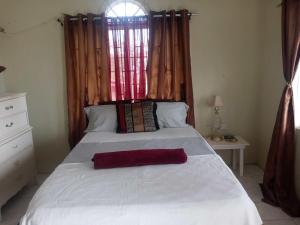 a bedroom with a large white bed with a window at Twin Court Retreat in Port Antonio