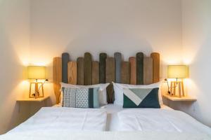 a bedroom with a large white bed with two lamps at QC Hotel Quartier Chiemsee in Seebruck