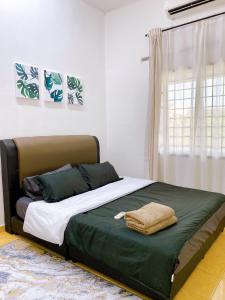1 dormitorio con 1 cama con manta verde y ventana en Mirahani Homestay Melaka, en Melaka