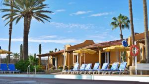 un complejo con sillas, palmeras y piscina en Bungalows Los Almendros - Exclusive Vacation Club, en Playa del Inglés