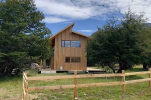 une maison en bois dans un champ avec une clôture dans l'établissement Preciosa casa V. Cerro Castillo cercana Parque, à Villa Cerro Castillo 13 autres photos