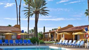 a resort pool with chairs and palm trees at Bungalows Los Almendros - Exclusive Vacation Club in Playa del Ingles