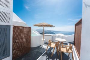 a balcony with a table and chairs and an umbrella at Cilon Suites Santorini in Imerovigli