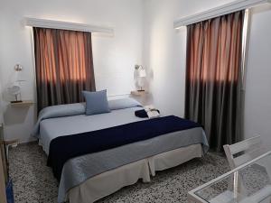 1 dormitorio con 1 cama con sábanas azules y ventanas en Pensión Playa, en Los Cristianos