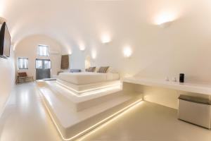 a white room with a bed and a table at Cilon Suites Santorini in Imerovigli