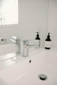 a white bathroom sink with a faucet and a mirror at Nelson Central Town House in Nelson