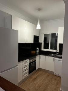 a kitchen with white cabinets and black counter tops at Vivienda con encanto, en un complejo con piscina in La Estrella