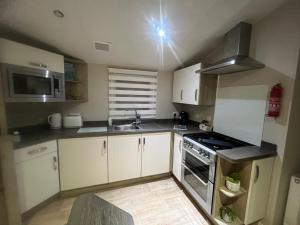 a kitchen with white cabinets and a stove top oven at Sky by the sea in Whitstable