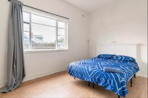 a bedroom with a bed with a blue comforter and a window at Richmond Private Rooms - 151 Hoddle Homestay in Melbourne