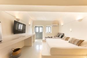 a white room with two beds and a flat screen tv at Cilon Suites Santorini in Imerovigli