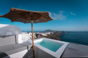 an umbrella sitting on a chair next to a swimming pool at Cilon Suites Santorini in Imerovigli