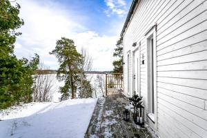 a white house with snow on the side of it at Relaxing Lake Oasis with Jacuzzi - Amazing view & Private Pier in Stockholm