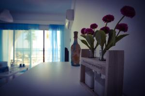 einen Tisch mit lila Blumen in einem Zimmer mit Fenster in der Unterkunft Krasas Beach Apartment Rentals in Larnaka