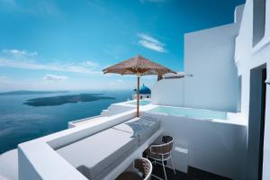 a white balcony with an umbrella and the ocean at Cilon Suites Santorini in Imerovigli