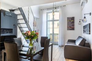 a living room with a staircase and a table with a vase of flowers at JEAN MÉDECIN - Modern Flat - Heart of center in Nice