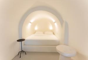 a white room with a bed and a toilet at Cilon Suites Santorini in Imerovigli