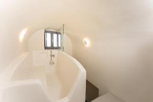 a white bath tub in a bathroom with a window at Cilon Suites Santorini in Imerovigli