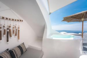 a bathroom with a soaking tub and an umbrella at Cilon Suites Santorini in Imerovigli