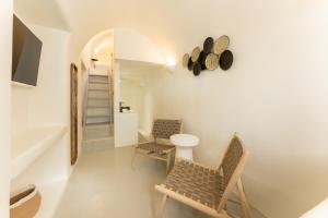 um quarto branco com duas cadeiras e uma mesa em Cilon Suites Santorini em Imerovigli