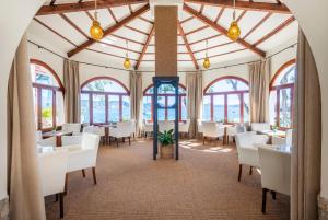 a dining room with white tables and chairs and windows at Hotel Cala Fornells in Paguera