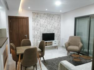 a living room with a table and chairs and a television at Sublime appartement le Palace Hammamet Nord Mrezga in Hammamet