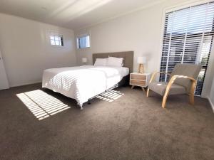 um quarto com uma grande cama branca e uma cadeira em Nelson City Town House 10 minute walk to town em Nelson